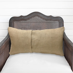 A brown wooden chair with a woven headrest and a beige pillow on the seat.