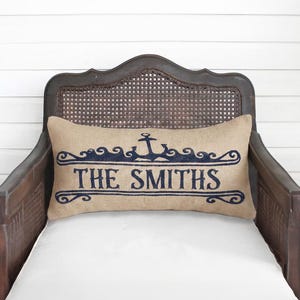 A wooden chair with a beige pillow featuring the text "THE SMITHS" in blue embroidery.