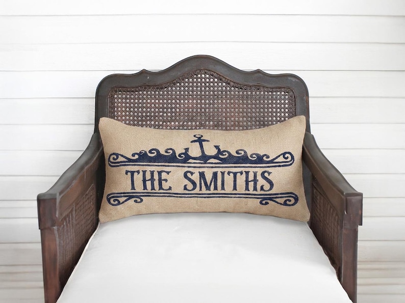 A wooden chair with a beige pillow featuring the text "THE SMITHS" in blue embroidery.