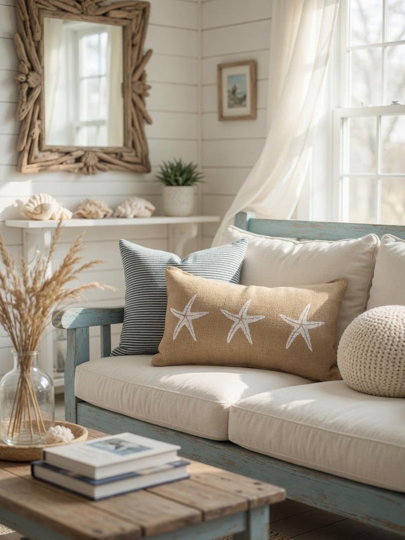 a cozy living room with a white sofa adorned with star-shaped throw pillows, a wooden coffee table, and a mirror on the wall. The room is decorated with a vase of dried flowers, a stack of books, and a potted plant, creating a warm and inviting atmosphere.