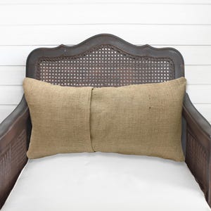 A brown wooden chair with a woven headrest and a beige pillow on the seat.