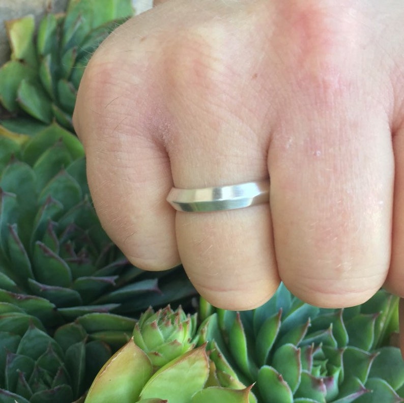 Peut inclure: Une bague en argent avec un design g&eacute;om&eacute;trique. La bague est port&eacute;e au doigt.