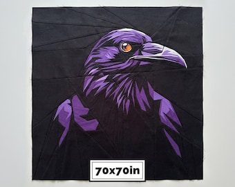 May include: A square fabric quilt block featuring a geometric raven design in shades of black and purple. The bird has a bright orange eye and a sharp beak. A white rectangular label at the bottom displays the text 70x70in.