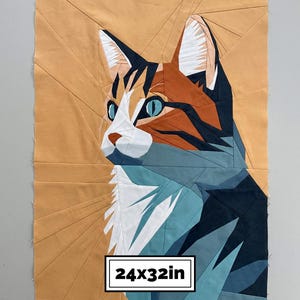 May include: A geometric fabric quilt block featuring a stylised cat portrait in shades of orange, dark blue, teal, and white. The design is composed of angular fabric pieces with a sunburst background. The text 24x32in is printed at the bottom.