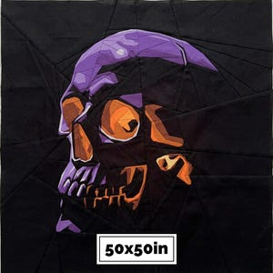 May include: A square fabric quilt block featuring a geometric, pieced skull design in shades of purple, orange, and black. The skull is constructed from angular fabric segments. A white rectangular label at the bottom displays the text 50x50in.