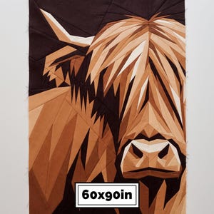 Può includere: Un blocco di trapunta in tessuto geometrico raffigurante un ritratto di mucca Highland in tonalità marrone, marrone chiaro e crema. Il design è composto da sezioni di tessuto angolari. Un'etichetta rettangolare bianca in basso mostra 60x90in.