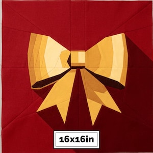 May include: A square fabric quilt block featuring a central golden yellow bow design against a deep red background. The bow is constructed from geometric fabric pieces in varying shades of yellow and gold. The block measures 16x16 inches.