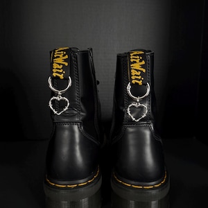 Puede incluir: Un letrero de madera hecho a mano con el texto "Welcome to our home" en un estilo manuscrito. El letrero está pintado de blanco con un marco teñido oscuro. Una pequeña planta verde se coloca en el letrero.