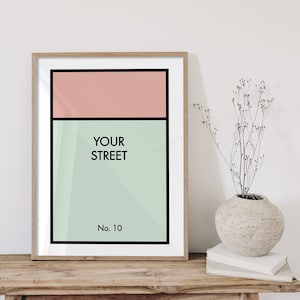 Puede incluir: Una impresión enmarcada con un diseño minimalista que presenta un esquema de color rosa y verde. La impresión dice "YOUR STREET" y "No. 10" en texto negro.