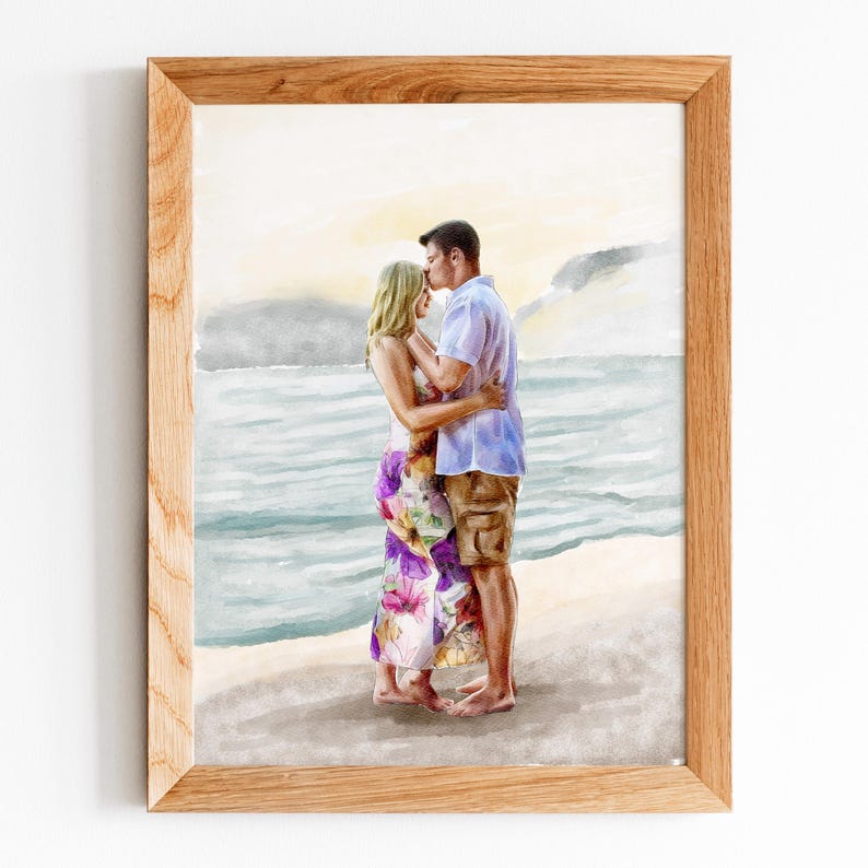 May include: A watercolour painting in a light wood frame depicting two figures standing on a sandy beach by the ocean. One figure wears a floral dress with purple and yellow tones, while the other wears a light blue shirt and tan shorts.