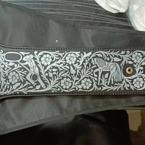 May include: A black leather boxing championship belt with gold accents and a large circular centre plate featuring the text "WBC Champion" and a colourful design of flags. The belt has a silver floral design with a horse and rider.