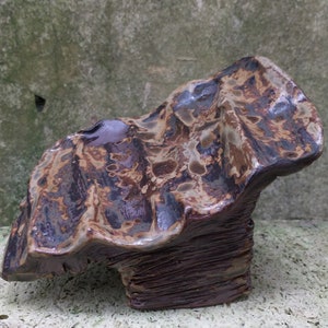 Op de afbeelding: Een keramisch beeldhouwwerk met een getextureerd, gelaagd oppervlak. Het beeldhouwwerk is bruin, zwart en wit met een glanzende afwerking.