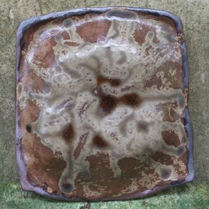 Op de afbeelding: Vierkant keramisch bord met een bruine en witte glazuur. De glazuur heeft een gevlekt, organisch patroon.
