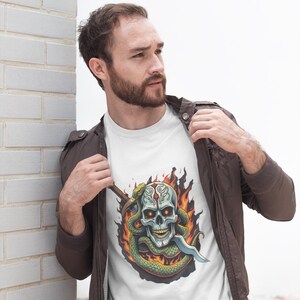 May include: White t-shirt with a graphic of a skull with a snake wrapped around it, the snake is holding a dagger, the skull is on fire.