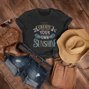 Camiseta unissex de algodão pesado, arte vibrante em quadro-negro 'Crie seu próprio sol', banner decorativo floral, letras inspiradoras desenhadas à mão
