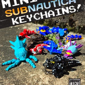 May include: A collection of articulated creature keychains in various colours including bright blue, black with white spots, red, and green. The text MINI SUBNAUTICA KEYCHAINS is displayed at the top, and a MAGNI MODELS logo is in the bottom corner.