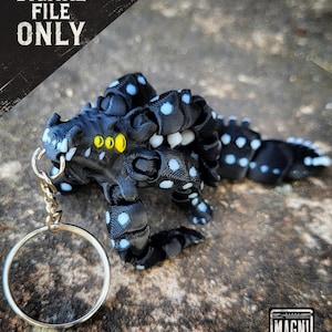May include: A black and white dragon keyring with blue polka dots and yellow eyes. The keyring is attached to a silver ring. The image includes the text "DIGITAL FILE ONLY".