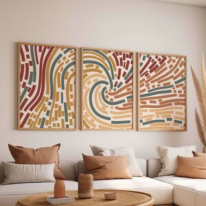 May include: Three framed abstract art prints with a geometric pattern of curved lines in shades of brown, yellow, green, and red on a cream background.