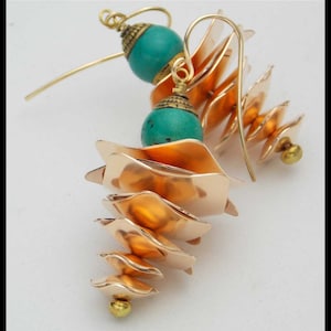 May include: A pair of gold earrings with turquoise beads and a cascading, layered design. The earrings are made of metal and have a unique, geometric shape.