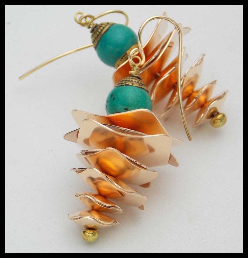 May include: A pair of gold earrings with turquoise beads and a cascading, layered design. The earrings are made of metal and have a unique, geometric shape.