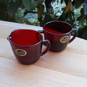 May include: Two red glass cups with gold lettering that reads "Royal Ruby Anchorware".