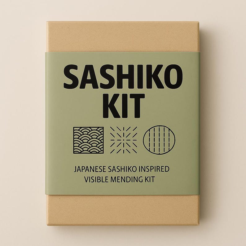 Puede incluir: Una caja de cart&oacute;n marr&oacute;n con una etiqueta verde que dice "SASHIKO KIT" y "JAPANESE SASHIKO INSPIRED VISIBLE MENDING KIT". La etiqueta tambi&eacute;n presenta tres dise&ntilde;os geom&eacute;tricos en blanco y negro.