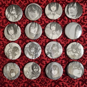May include: A set of 16 round black and white buttons featuring different characters from the anime Attack on Titan. The buttons are arranged in a grid pattern on a red background.