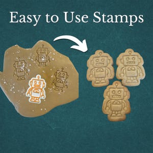 May include: Image shows robot-shaped cookie stamps and cookies. The text "Easy to Use Stamps" is at the top. The stamps are used on dough, and the finished cookies are displayed. The robot cookies are light brown.