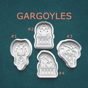 May include: Four white plastic cookie cutters shaped like gargoyles on pedestals, labeled #1 through #4. The text GARGOYLES is printed in light orange at the top. Each cutter features a distinct winged creature design with intricate architectural details.