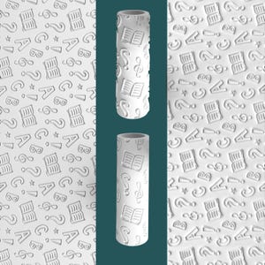 May include: White cylindrical rolling pin with embossed designs of books, musical notes, question marks, and the letters A and B. The background features a repeating pattern of the same symbols. The rolling pin is approximately 8 inches tall.