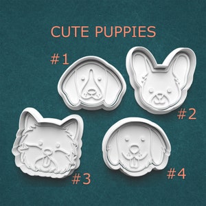 May include: Four white plastic cookie cutters in the shape of dog faces. The cutters are labeled #1, #2, #3, and #4. The text "CUTE PUPPIES" is above the cutters in orange letters. The background is a teal color.