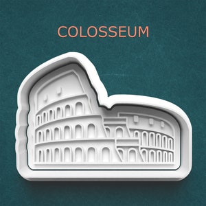 May include: A white Colosseum-shaped cookie cutter with the word "COLOSSEUM" in orange text above it. The cutter features detailed architectural elements of the Roman amphitheater, set against a teal background.