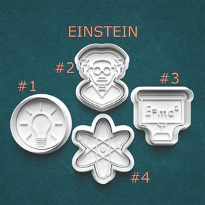 May include: White plastic cookie cutters shaped as a lightbulb, Albert Einstein, an atom, and a chalkboard with the formula E=mc&sup2;. The word "EINSTEIN" is printed in orange above the cookie cutters.