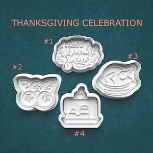 May include: Four white plastic cookie cutters for Thanksgiving. The cutters include a design that says "Happy Thanksgiving", a blueberry design, a turkey, and a piece of cake. The words "Thanksgiving Celebration" are at the top.