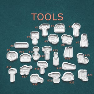 May include: A collection of white plastic tool-shaped cookie cutters. The word "TOOLS" is displayed in orange at the top. The cutters include a hammer, wrench, saw, drill, and more. The tools are numbered from 1 to 23.