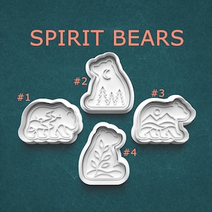 May include: Four white plastic cookie cutters labeled SPIRIT BEARS. Cutter #1 features a bear with a forest scene, #2 shows a bear with a crescent moon and trees, #3 depicts a bear with mountains and a sun, and #4 displays a bear with a leafy branch.