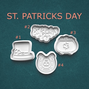 May include: White St. Patrick's Day themed cookie cutters. The set includes a leprechaun hat, a horseshoe with a shamrock, a pot of gold with a shamrock, and a cloud-shaped cutter with the text "St. Patrick's Day".