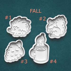 May include: Four white plastic cookie cutters in fall shapes: a hedgehog, a squirrel, a pine cone, and a steaming mug of coffee. The word "FALL" is printed above the cutters. Each cutter is numbered.