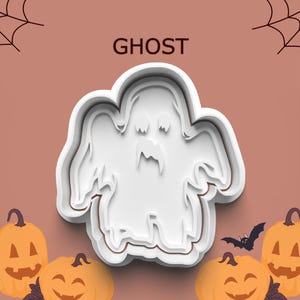 May include: White ghost-shaped cookie cutter with the word "GHOST" above it. The image also includes orange pumpkins and a black bat, all set against a brown background. A Halloween-themed design.