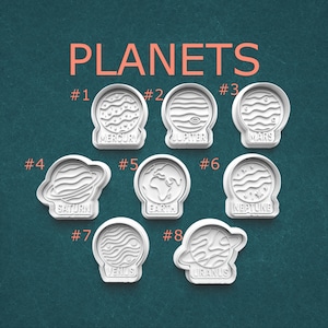 May include: White plastic cookie cutters shaped like planets, including Mercury, Jupiter, Mars, Saturn, Earth, Neptune, Venus, and Uranus. The word "PLANETS" is written in orange at the top of the image.