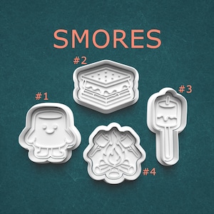 May include: Four white plastic cookie cutters in the shape of s'mores ingredients. The cutters include a marshmallow, a graham cracker sandwich, a marshmallow on a stick, and a campfire. The word "SMORES" is written in orange.