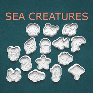 May include: White plastic cookie cutters in various sea creature shapes, including a seashell, whale, turtle, lobster, seahorse, and starfish. The words "SEA CREATURES" are in orange text at the top.
