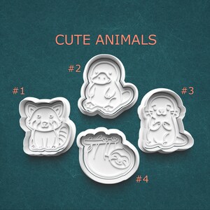 May include: Four white plastic cookie cutters in the shapes of cute animals: a red panda, a platypus, an otter, and a sloth. The words "CUTE ANIMALS" are printed above the cookie cutters.