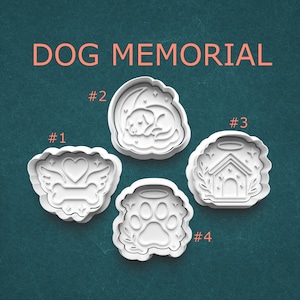 May include: Four white plastic cookie cutters with dog-themed designs. The cutters include a heart with wings and a bone, a sleeping dog, a dog house, and a paw print. The words "DOG MEMORIAL" are printed in orange.