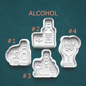May include: Four white plastic cookie cutters in the shape of alcoholic beverages. The shapes include a beer mug and bottle, a whiskey bottle and glass, a wine bottle and glass with grapes, and a cocktail.