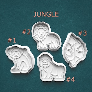 May include: White plastic cookie cutters in the shapes of a monkey, lion, leaf, and gorilla. The word "JUNGLE" is printed in orange above the cutters. Numbers are printed next to each cutter.