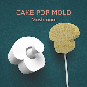 May include: A white mushroom-shaped cake pop mold next to a yellow mushroom cake pop on a stick. The text "CAKE POP MOLD Mushroom" is displayed in pink above the objects. The background is a teal color.