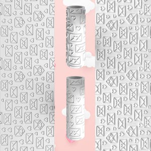 May include: White embossing rolling pin with a repeating pattern of envelopes and hearts. The image also shows a matching embossed pattern. The rolling pin is cylindrical and has a textured surface. The background is a light pink with white clouds.