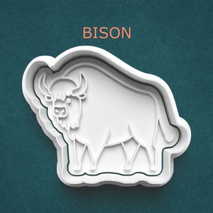 May include: A white plastic bison-shaped cookie cutter. The word "BISON" is printed in orange above the cutter. The cutter has a detailed outline of a bison with horns and a shaggy mane.