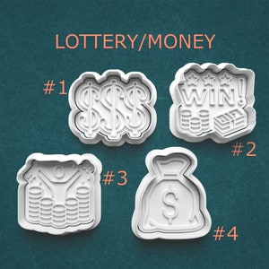 May include: Four white plastic cookie cutters with lottery and money themes. Designs include dollar signs, a "WIN!" graphic with coins and cash, a person with arms raised over coins, and a money bag with a dollar sign.